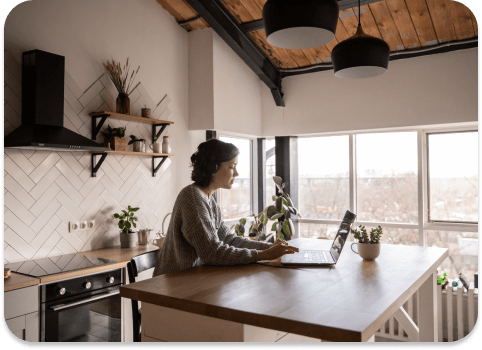 A woman working at a laptop in a bright, freshly painted kitchen